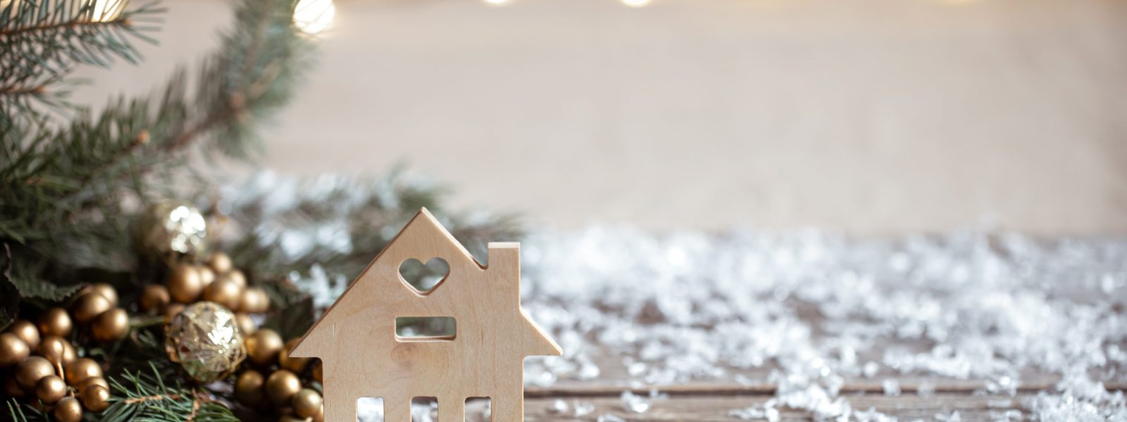 Winter cozy background with festive decor details, snow on a wooden table and bokeh. The concept of a festive atmosphere at home.
