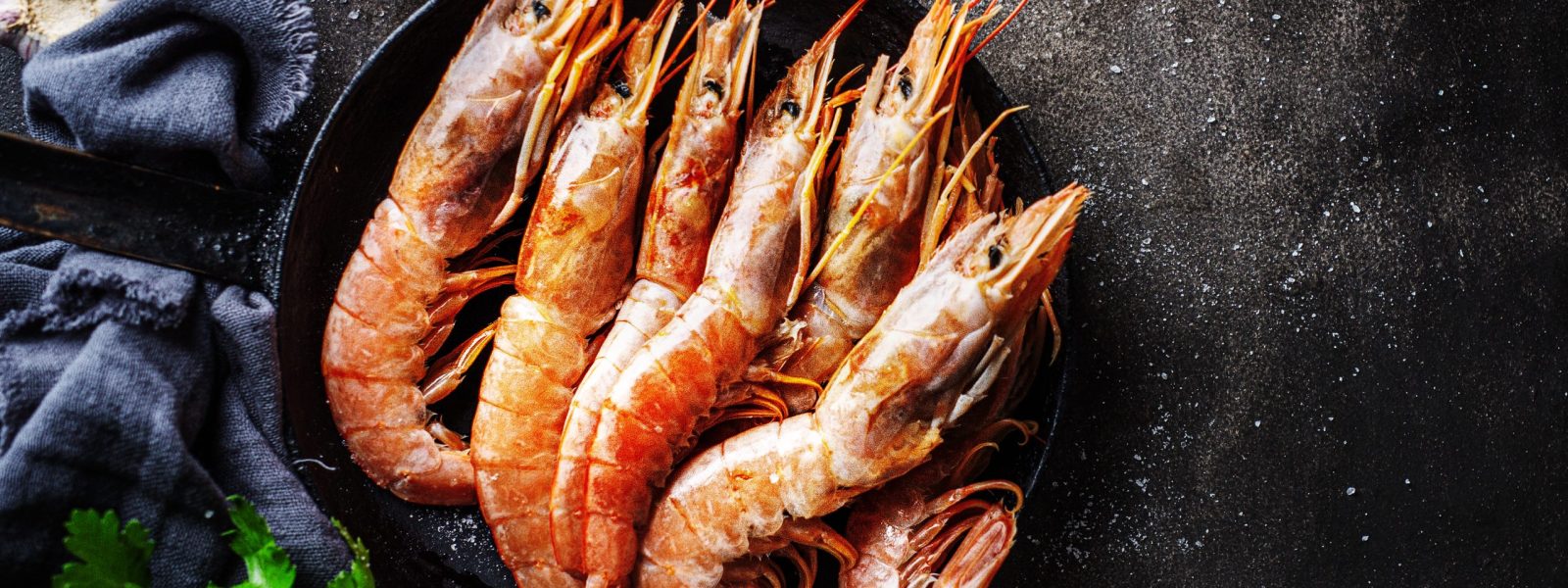 Raw giant king shrimps with ingredients ready for cooking on dark table. View from above.