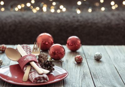 Close up of Christmas festive table setting on blurred dark background with bokeh, copy space.