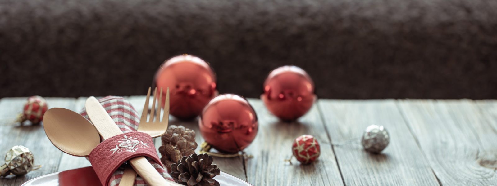 Close up of Christmas festive table setting on blurred dark background with bokeh, copy space.