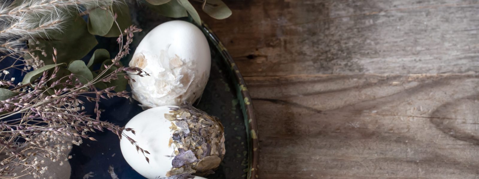 Easter eggs with dried flowers on a wooden table. Happy Easter concept.